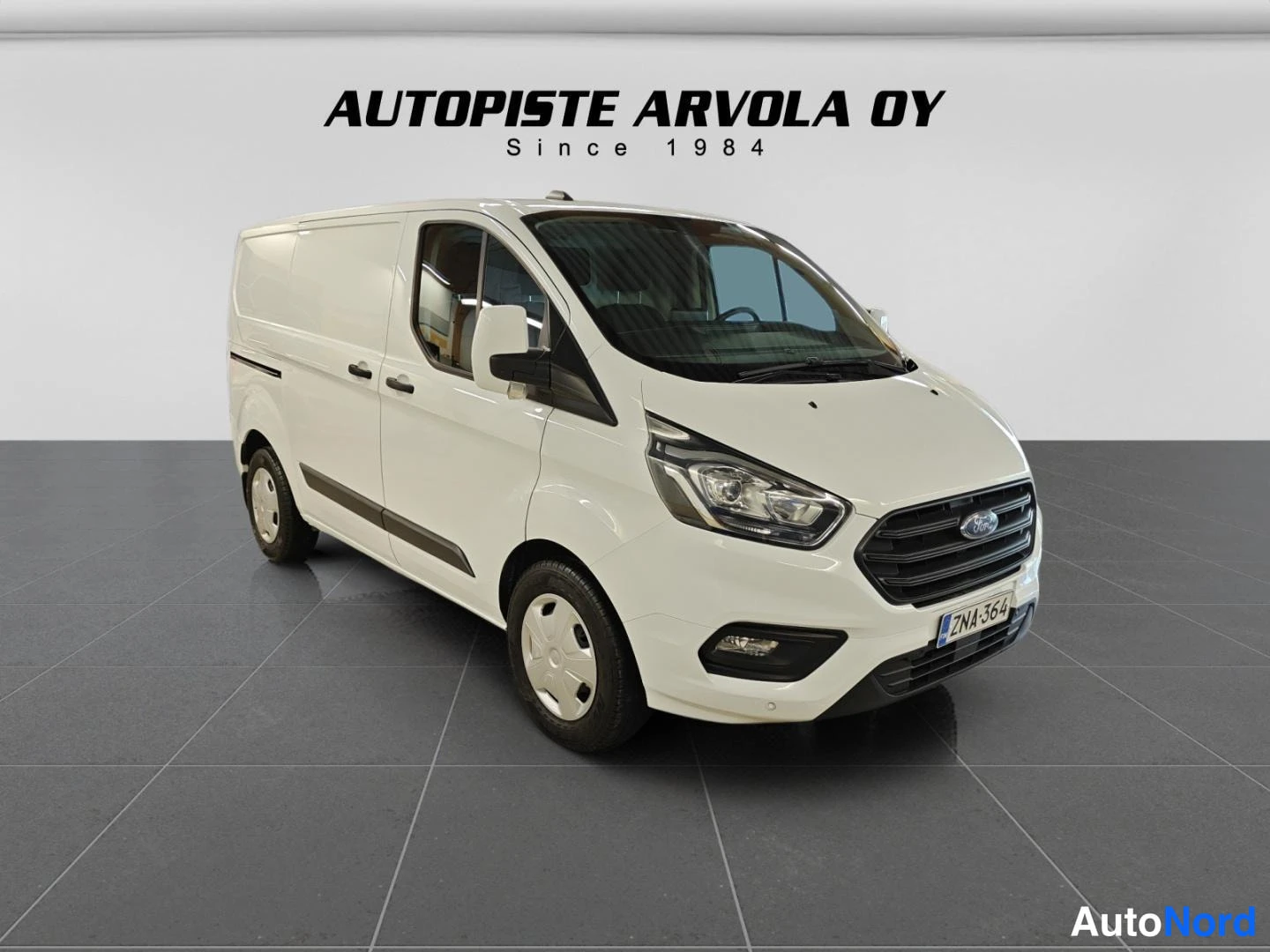 Etuviisto, nokka oikealle: Ford Transit Custom -pakettiauto valkoisena edestä oikealta kuvattuna.