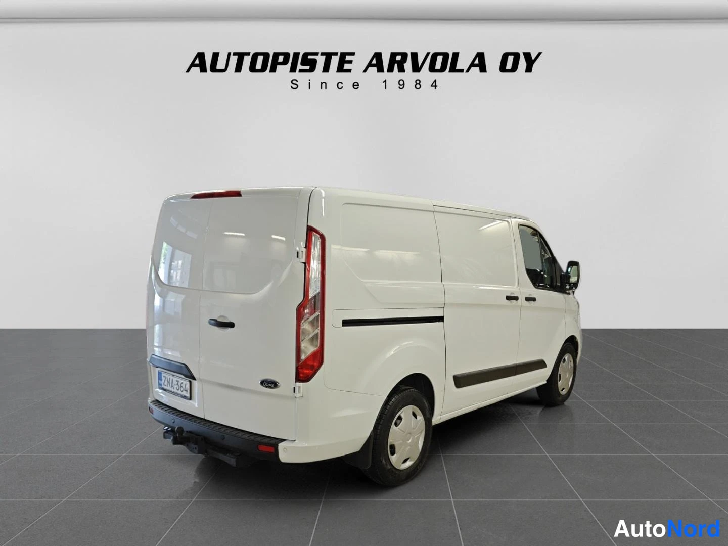 Takaviisto: Ford Transit Custom -pakettiauto valkoisena takaa vasemmalta kuvattuna.