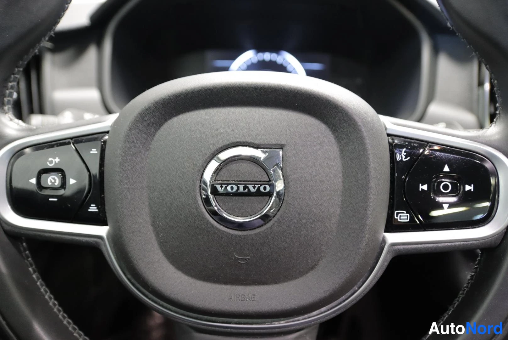 Muu: Lähikuva Volvon ohjauspyörästä; keskellä VOLVO-merkki ja AIRBAG-teksti, sivuilla monitoimipainikkeet.
