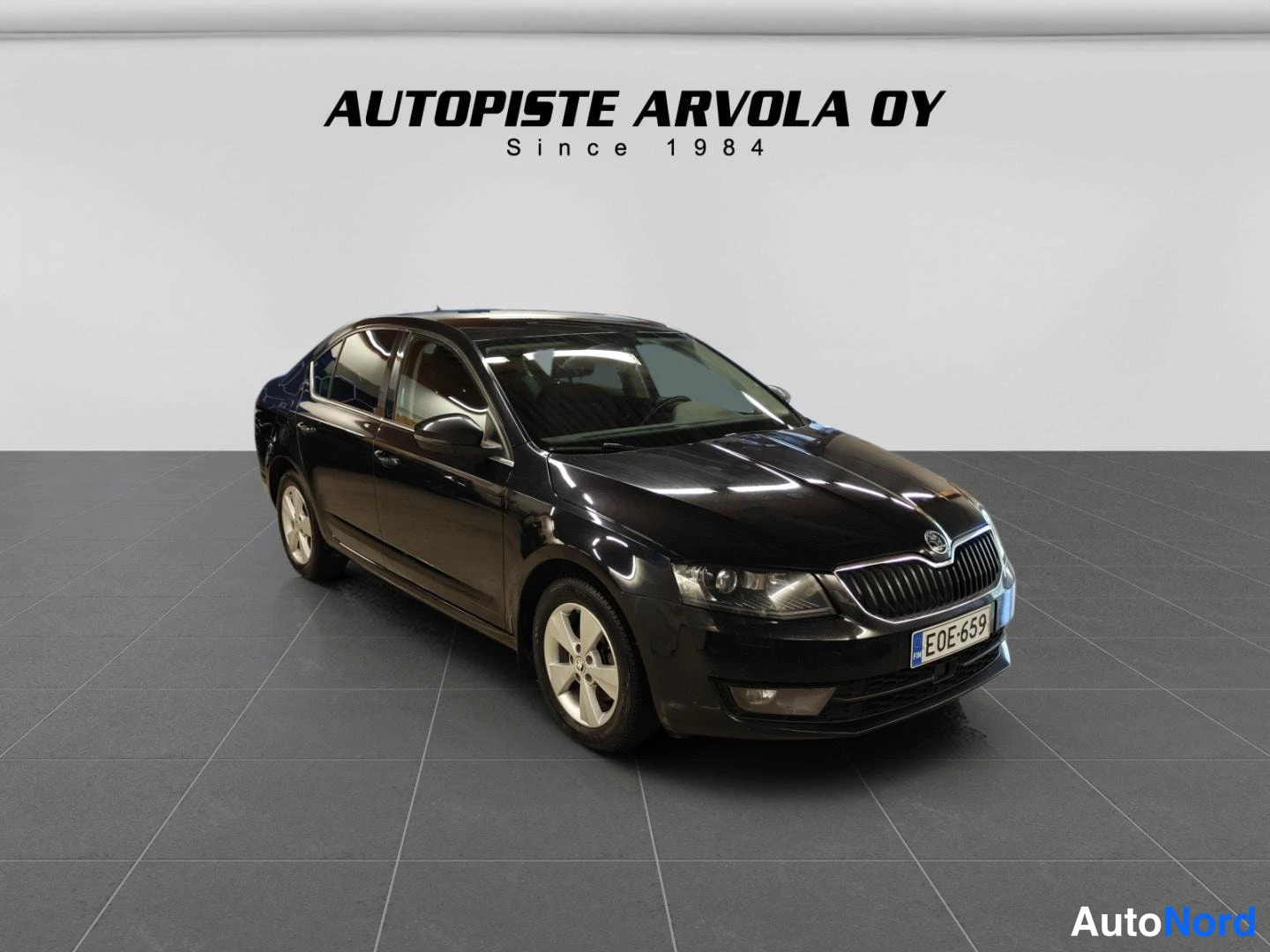 Etuviisto, nokka oikealle: Musta Skoda Octavia -sedan etukulmasta oikealta, rekisterikilpi.