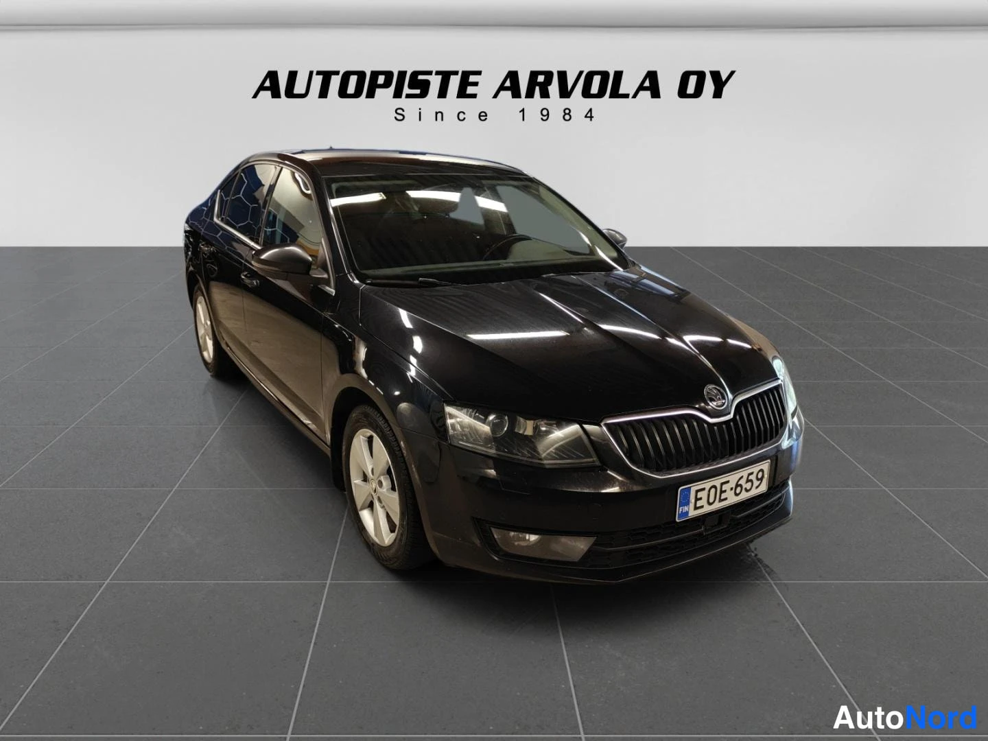 Etuviisto, nokka oikealle: Mustan Škoda Octavia -sedanin etukulma kuvattuna oikealta, rekisterikilpi.