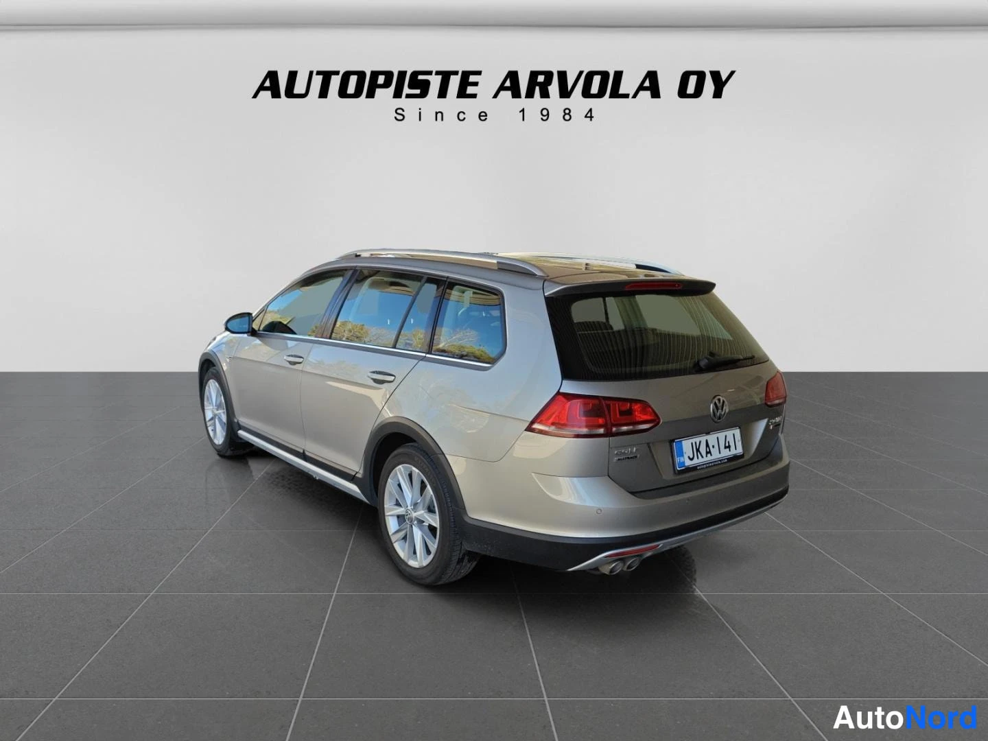 Takaa: Volkswagen Golf Variant takaa hieman sivulta kuvattuna studiossa, hopeanbeige autti, rekisterikilpi, AUTUPISTE ARVOLA OY logo taustalla.
