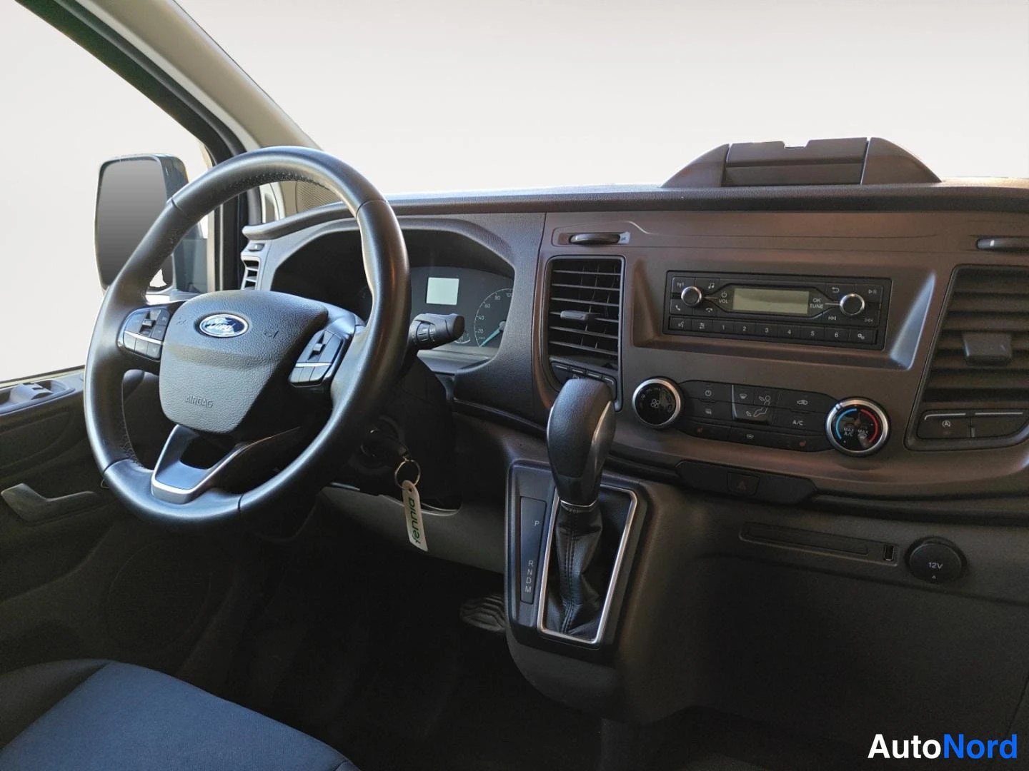 Etuistuimet: Ford Transit Customin kojetaulu vasemmalta: monitoimiohjauspyörä, automaattivaihteen valitsin, radio ja manuaalinen ilmastointi.