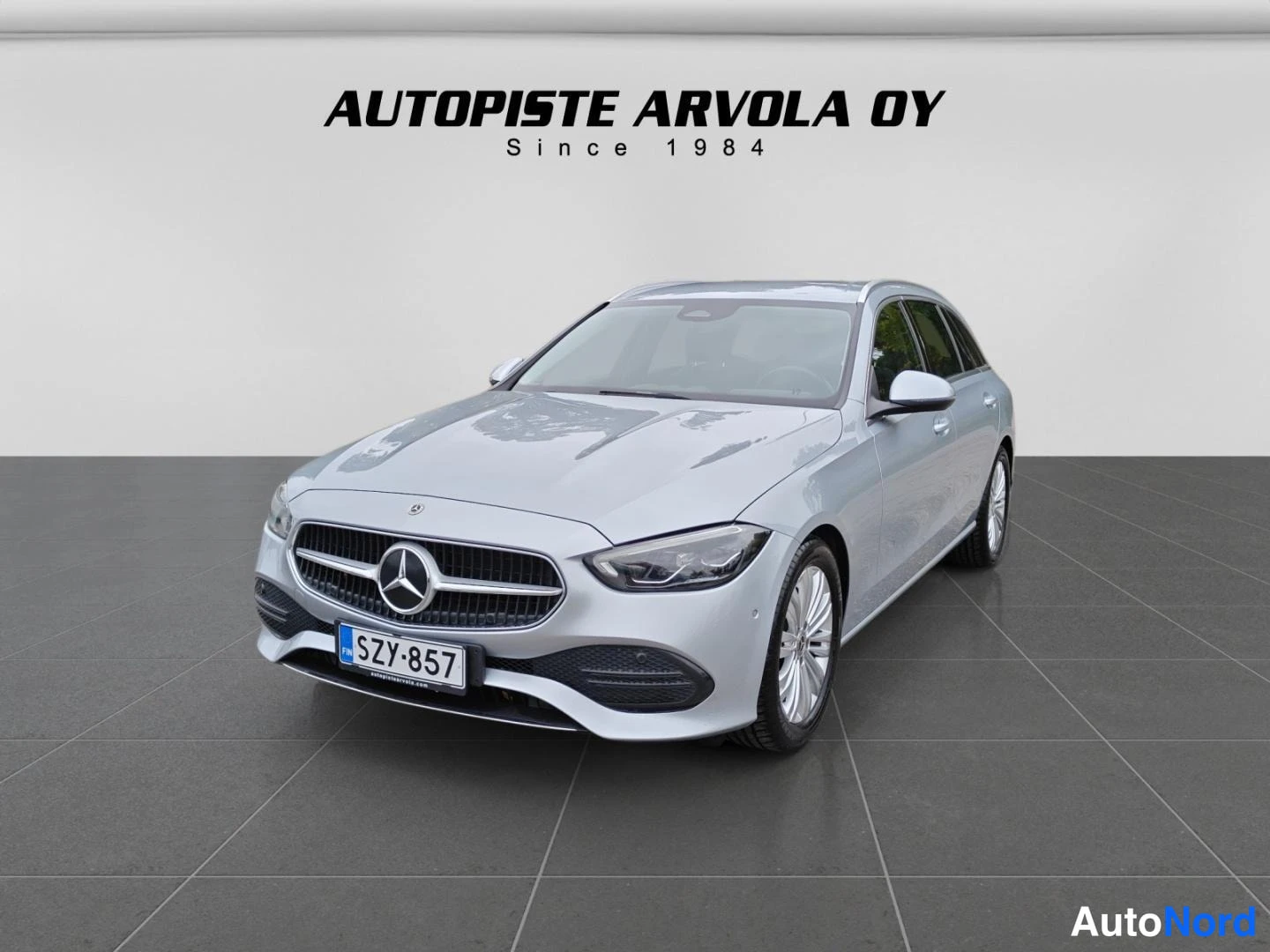 Etuviisto, nokka vasemmalle: Hopeanharmaa Mercedes-Benz C-sarjan farmari etuosa vasemmalta kuvattuna