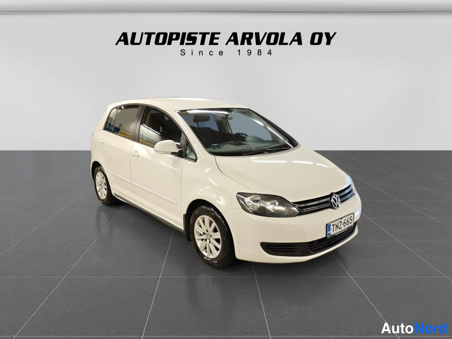 Etuviisto, nokka oikealle: Valkoinen Volkswagen Golf Plus -henkilöauto etuviistosta sisätiloissa, rekisteritunnus.