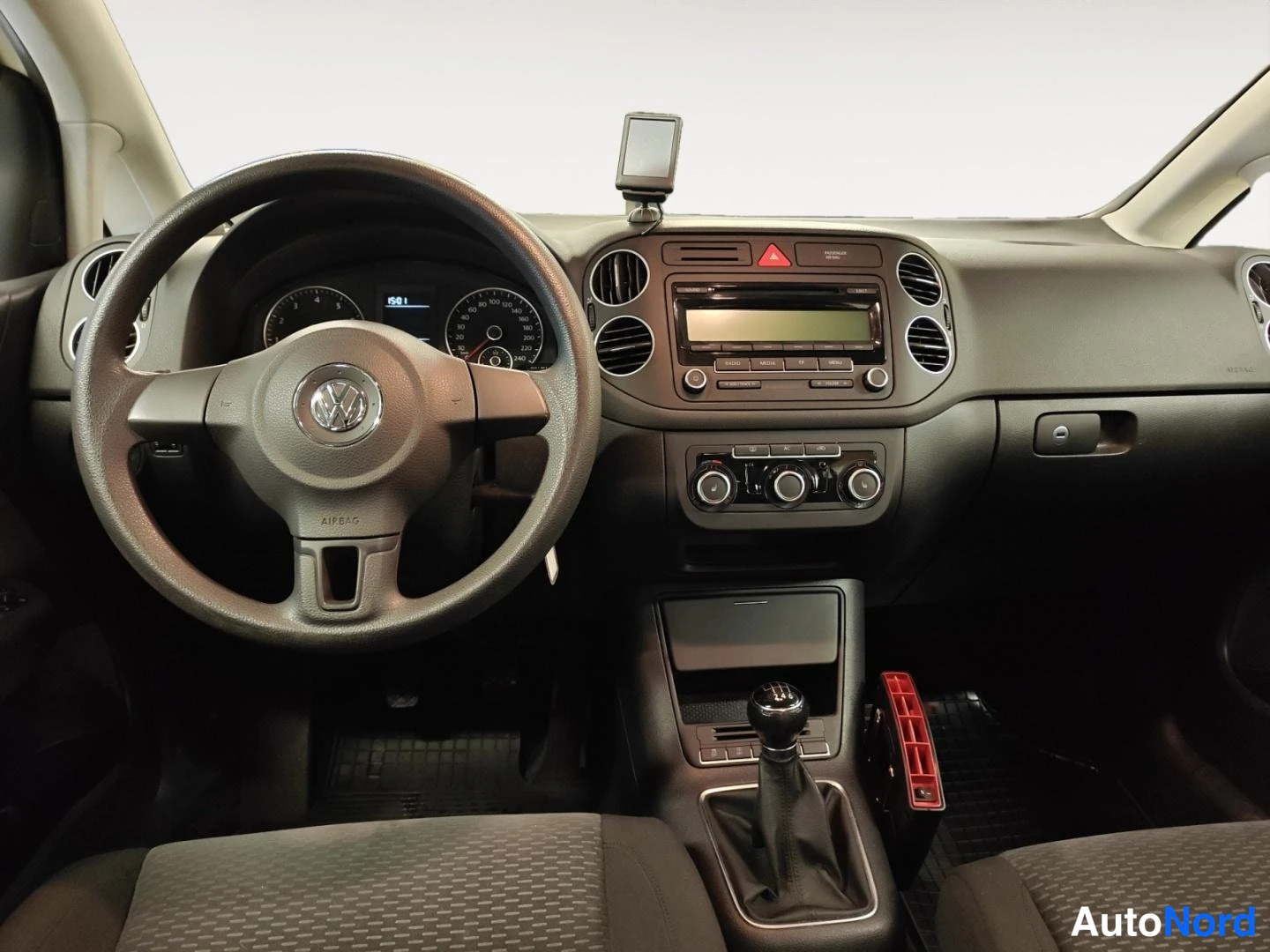 Edestä: Kojetaulu suoraan edestä: VW-ohjauspyörä, mittaristo, radio ja manuaalivaihteen keila.