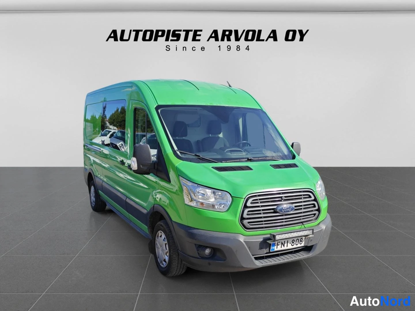 Etuviisto, nokka oikealle: Ford Transit -pakettiauto edestä oikealta vihreänä studiovalokuvassa