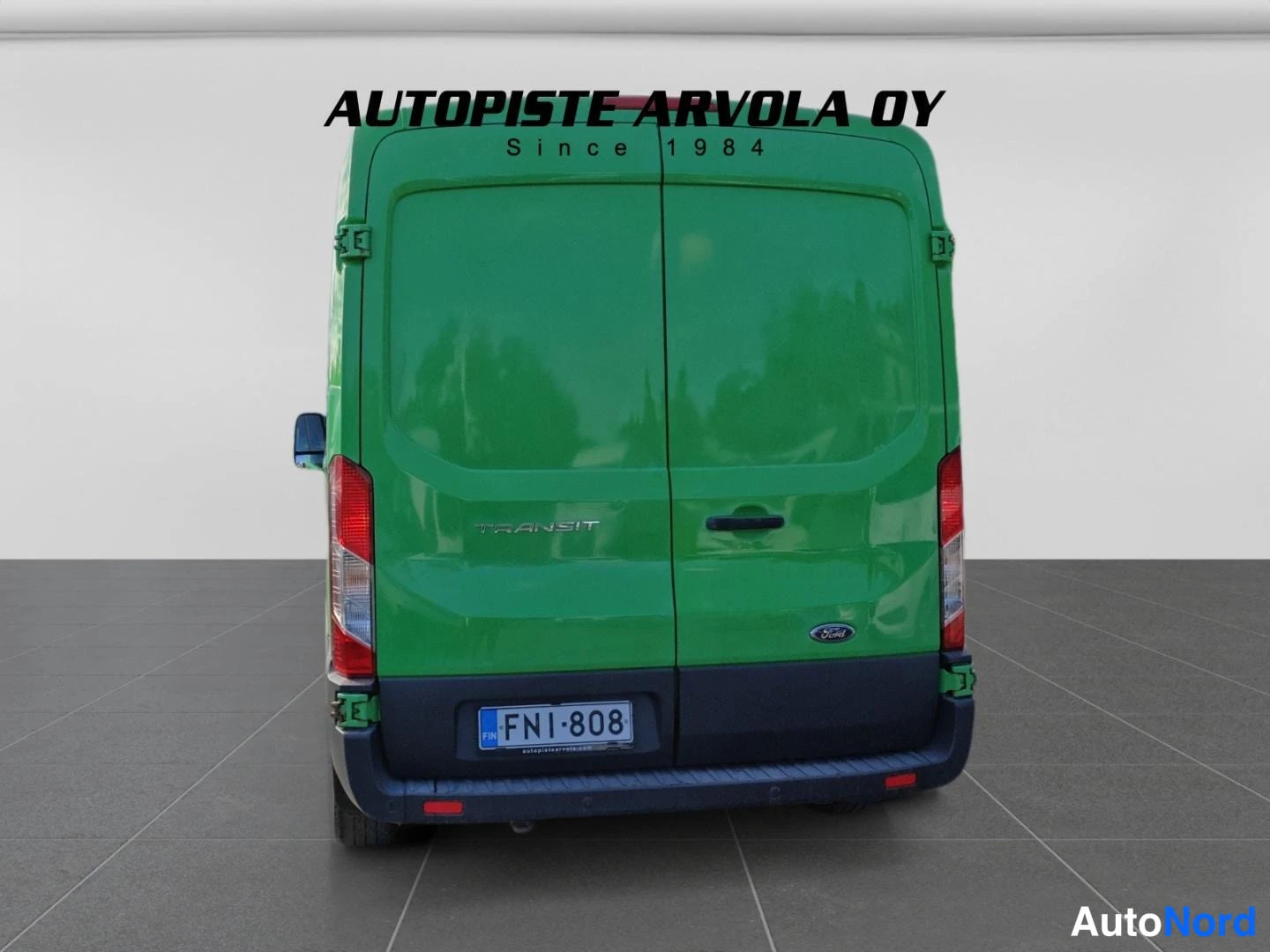 Takaa: Ford Transit -pakettiauton takaosa suoraan takaa kuvattuna; vihreä koripohja, kaksi takaluukku, punaiset takavalot, rekisteritunnus.
