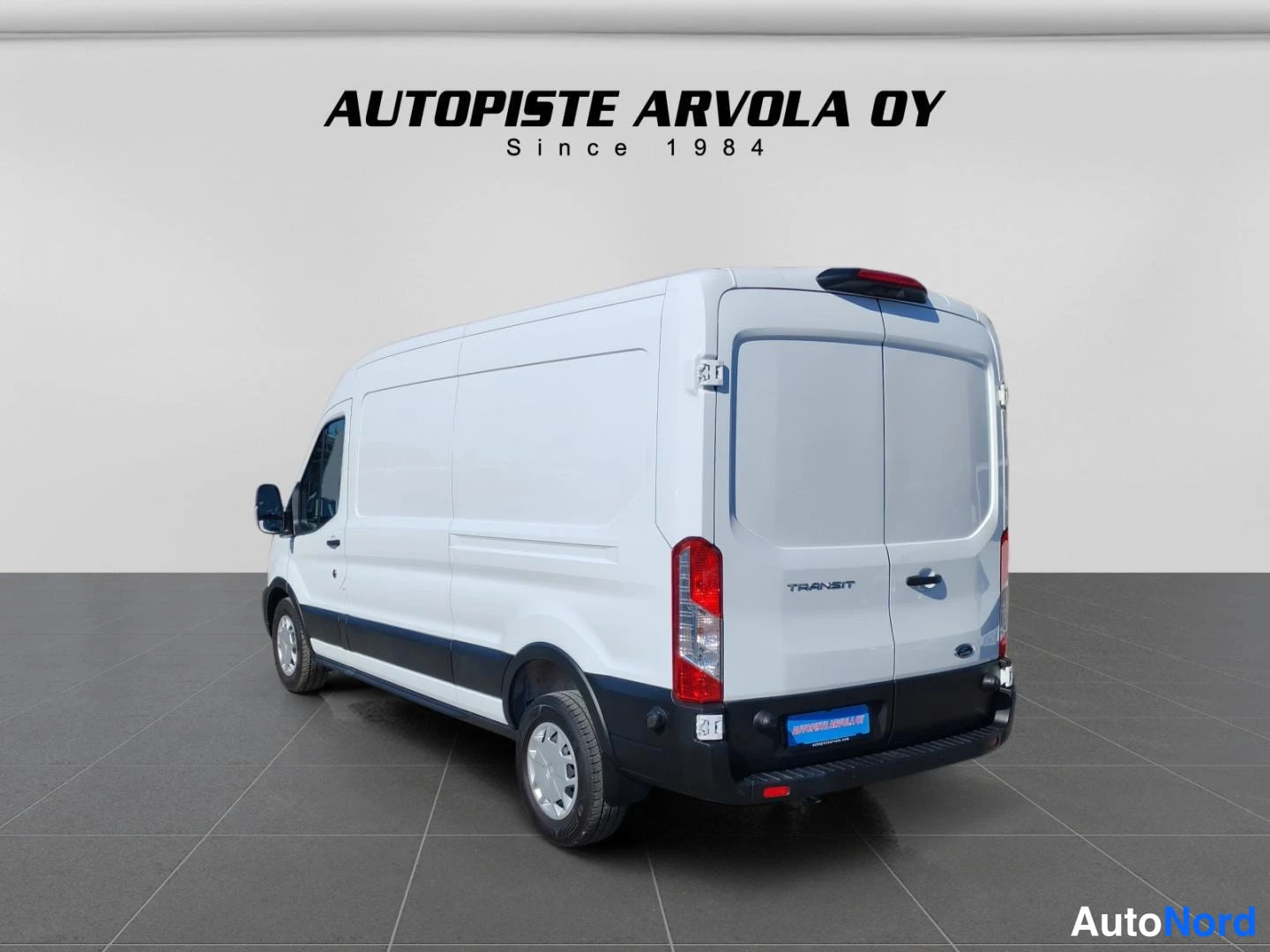 Takaviisto: Ford Transit -pakettiauto takaa vasemmalta valokuvattuna, kaksiosaiset takaovet ja korkealla sijaitseva lisäjarruvalo.