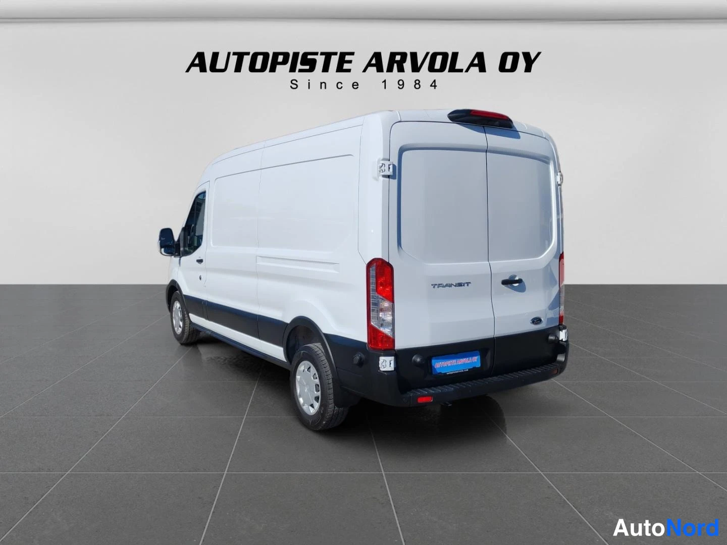 Takaviisto: Ford Transit -pakettiauto takaa vasemmalta valokuvattuna, kaksiosaiset takaovet ja Transit-kirjoitus.