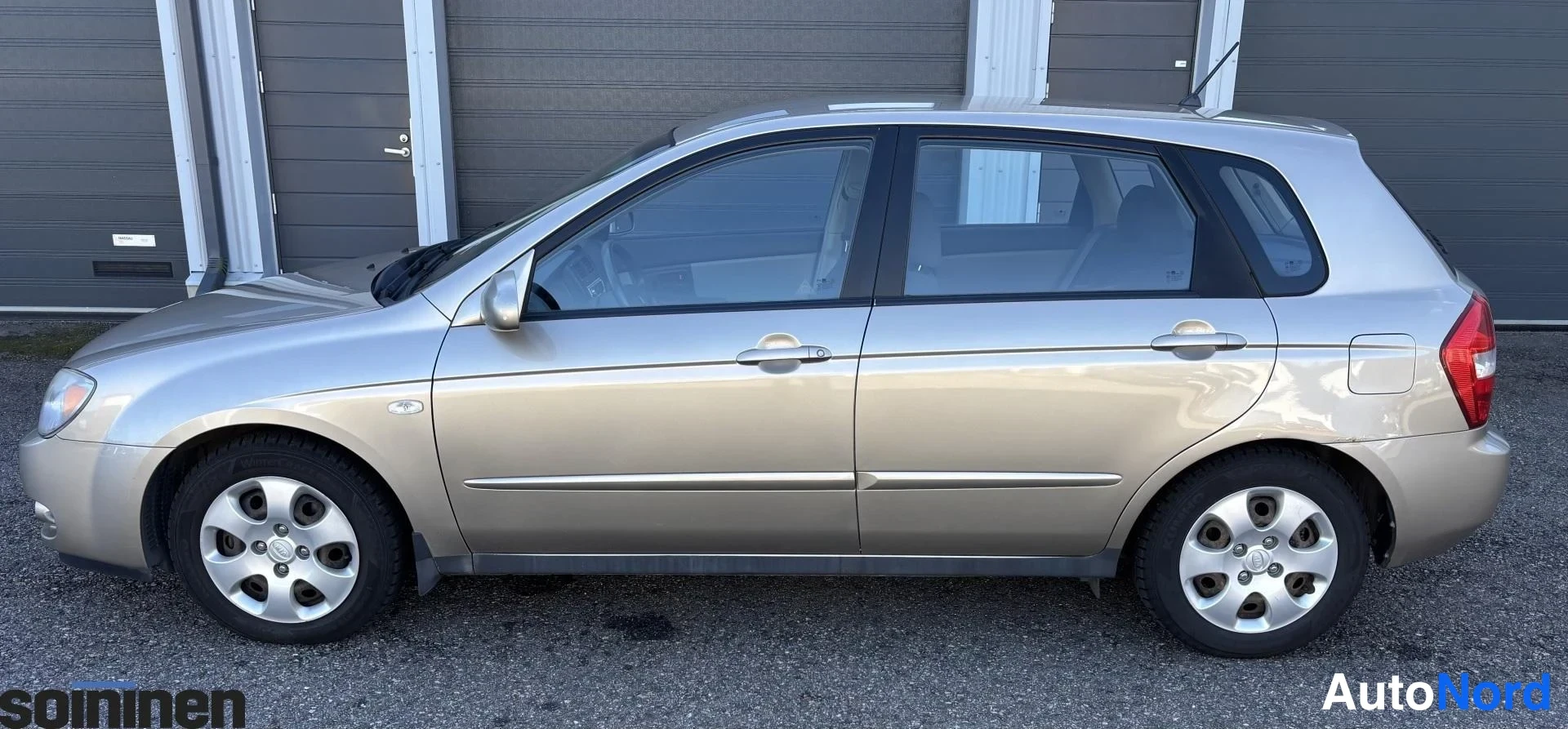 Etuviisto, nokka vasemmalle: Kia Cerato -viistoperäinen auto sivusta edestä vasemmalle kuvattuna, beige kori.