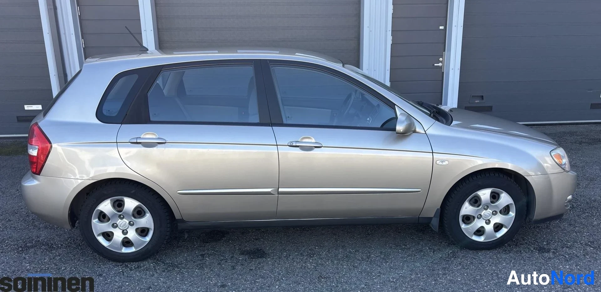 Takaviisto: Kia Cerato -viistoperäinen auto takaa oikealle kuvattuna, beige kori.