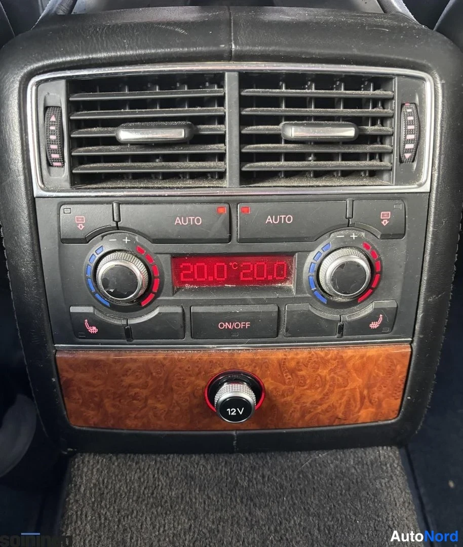 Muu: Ajoneuvon kojelaudan ilmastointipaneeli: kaksi AUTO-säädintä, näytössä 20.0 °C molemmilla puolilla, ON/OFF-painike ja puupanelissa 12 V-pistorasia.
