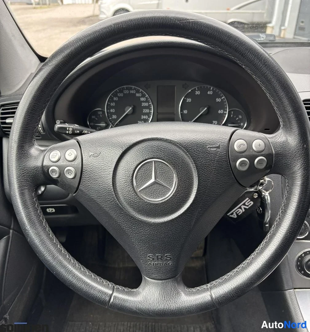 Edestä: Mercedes-Benzin ohjauspyörä ja mittaristo lähikuvana; pyörän napaan merkitty SRS AIRBOT ja takaa näkyvät mittarit.