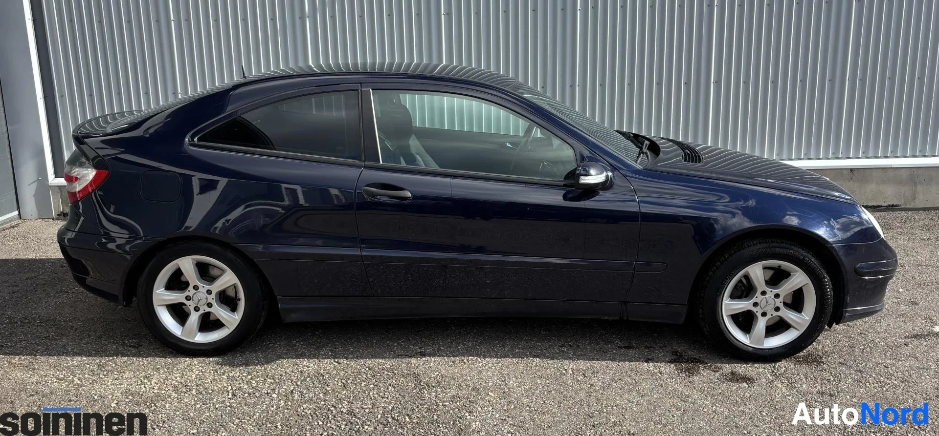 Takaviisto: Sinimusta henkilöauto takaviistosta, takaosa ja kylki näkyvissä.