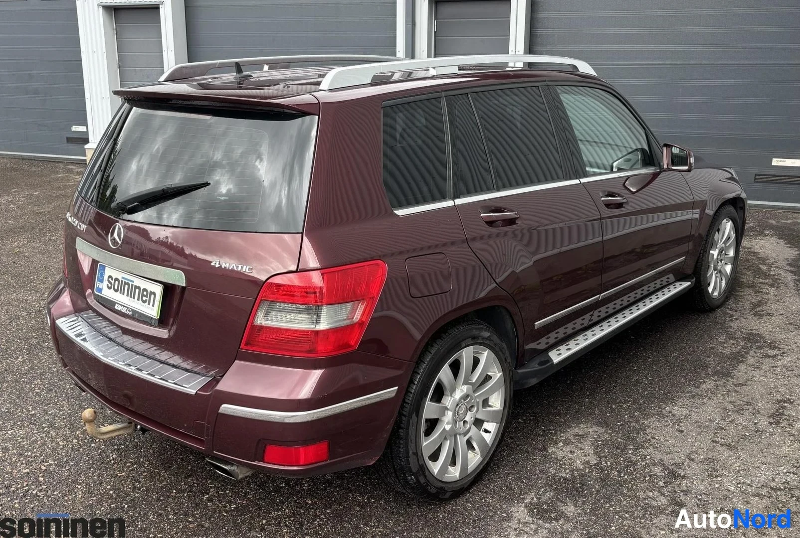 Takaviisto: Takakulma auto Mercedes-Benz GLK 320 CDI 4MATIC. Kuvassa on peräkärryteline, alumiinivanteet, katto- ja sivupakit. Punaruskea runko näkyy tässä näkymässä takana