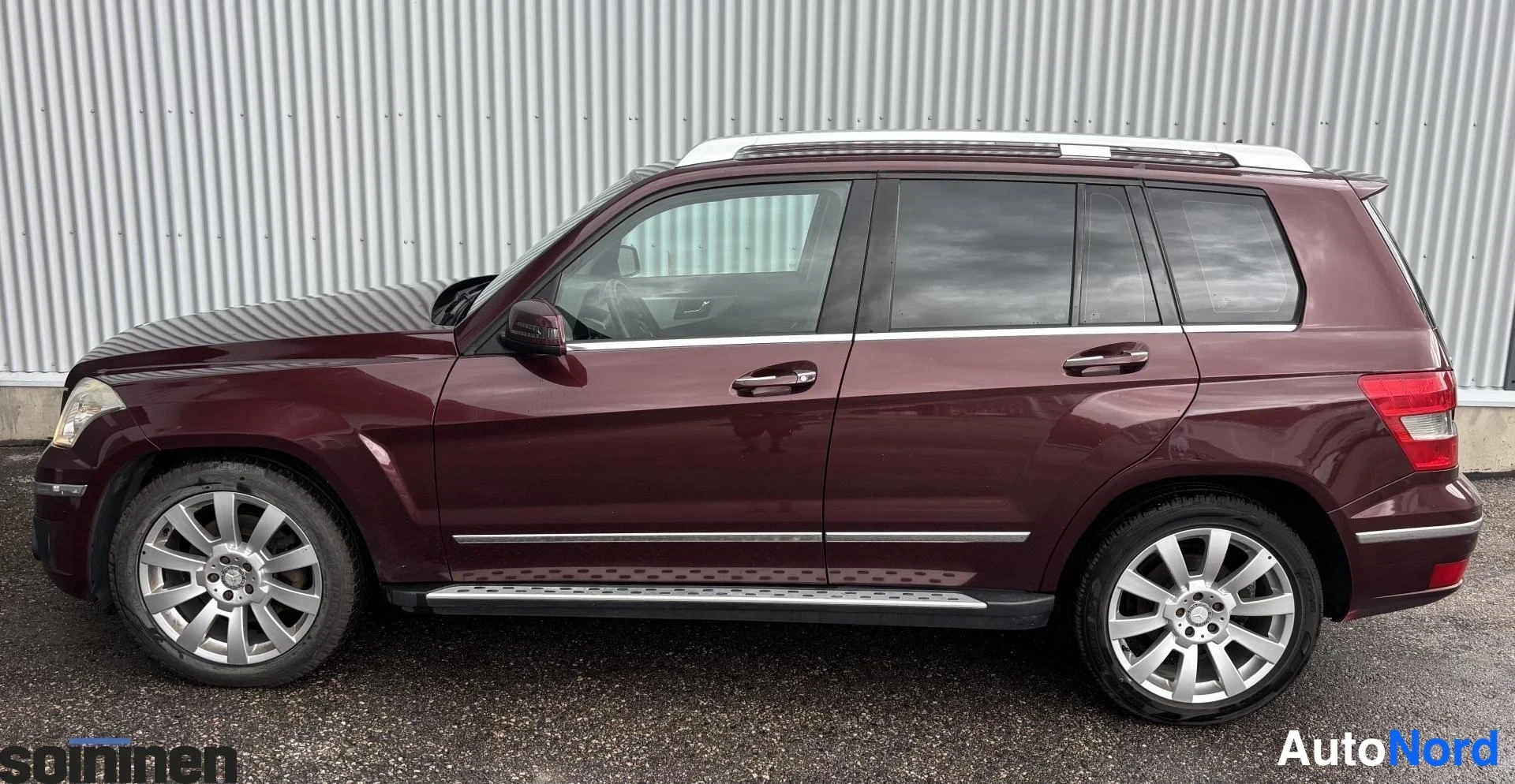 Sivulta: Mercedes-Benz GLK:n kylki- ja keulaosakuva: tummanpunainen koripaneeli, kattokaiteet, hopeiset astinlaudat ja monipinnaiset alumiinivanteet.