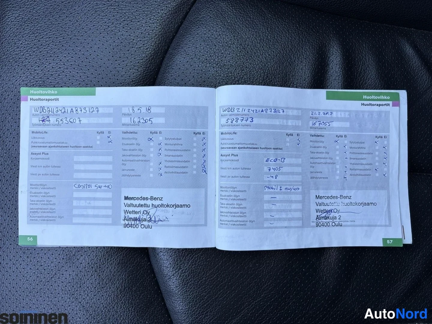 Yksityiskohta: Musta nahkapenkillä avattu Mercedes-Benzin huoltovihko sivuilla 56–57, huoltomerkinnät päivämäärillä 18.5.18 ja 21.2.2019 ja leima Mercedes-Benz Valtuutettu huo