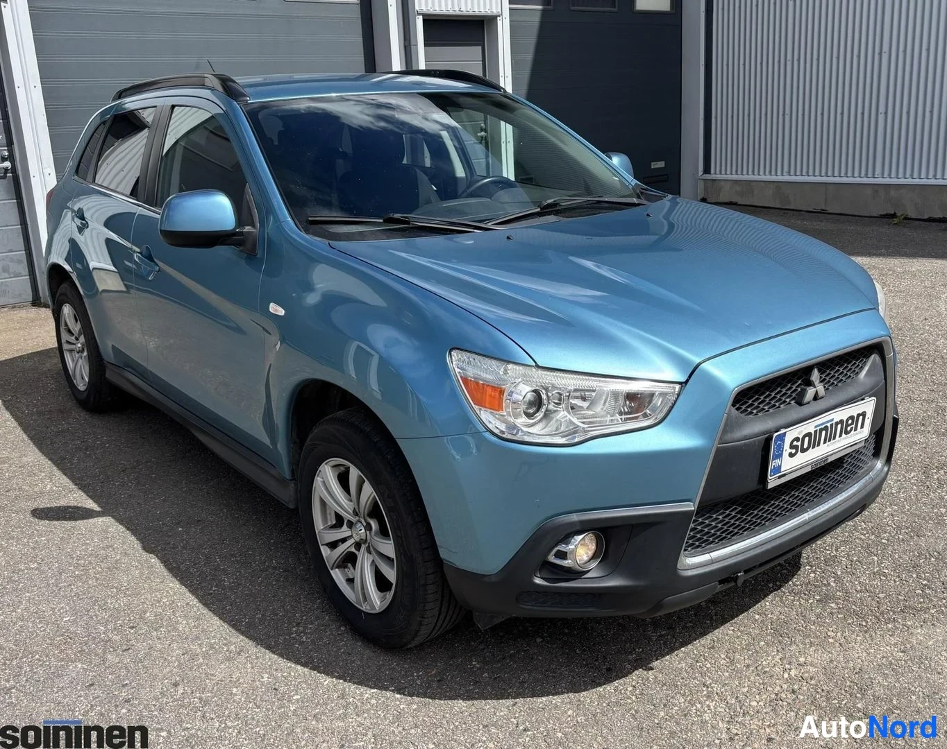 Etuviisto, nokka oikealle: Sinivihreä Mitsubishi-korkeatila-auto kolmesta neljästä kulmasta edestä, jossa etusäleikkö ja oikea päätyvalo ovat näkyvissä. Kuvassa on hopeiset vante