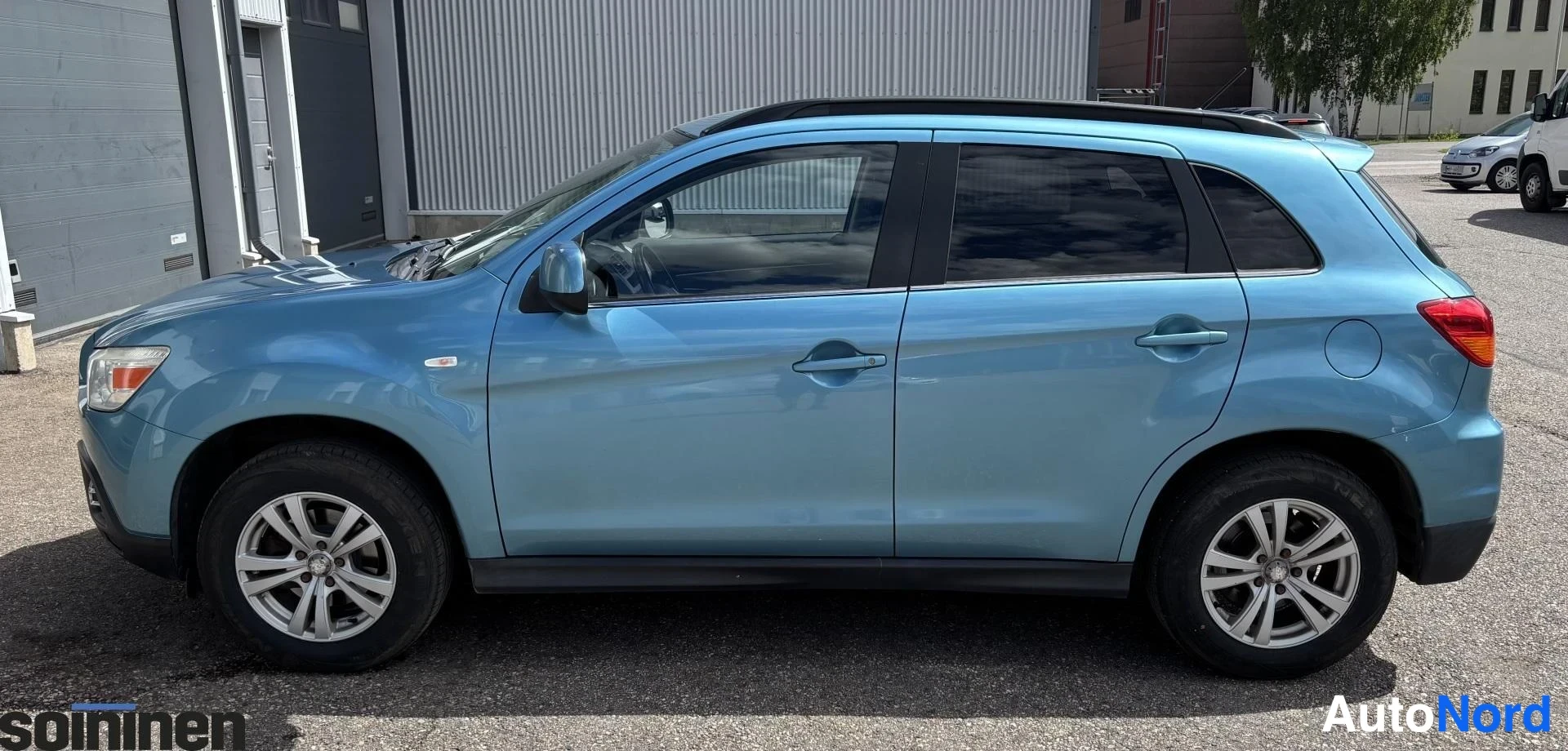 Etuviisto, nokka vasemmalle: Sininen Mitsubishi ASX -farmariauto sivulta etukulmasta, etusäleikkö kuvan vasemmassa laidassa.