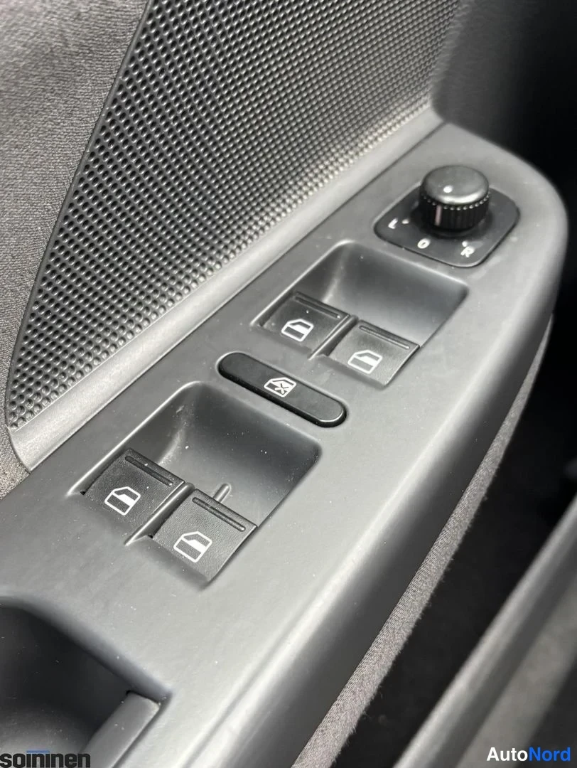 Yksityiskohta: Auto-oven sisäpaneelin lähikuva: ikkunanostinkytkimet, pyyhintäkytkin ja pyöreä sivupeilin säätönuppi tummassa muovipaneelissa.