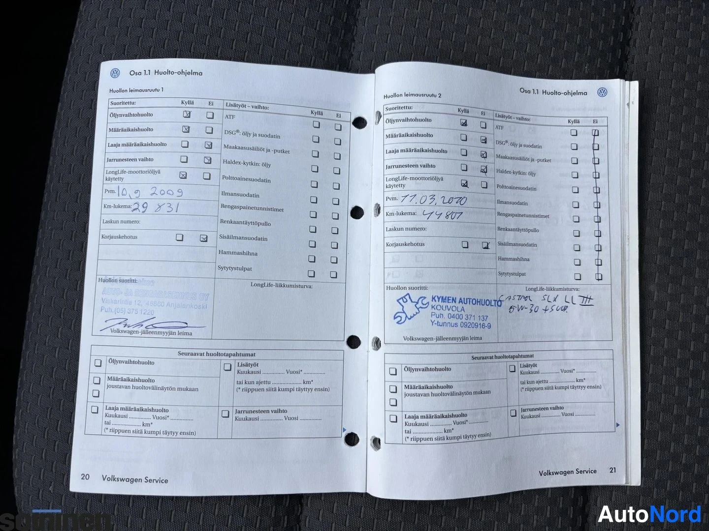 Yksityiskohta: Avoin Volkswagen-huoltokirja, sivut 20-21, huoltoleimasuruvut täytettyinä käsin kirjoituksin (10.9.2009 ja 17.3.2010) ja Kymmen Autohuolto Kouvolan leimoin.