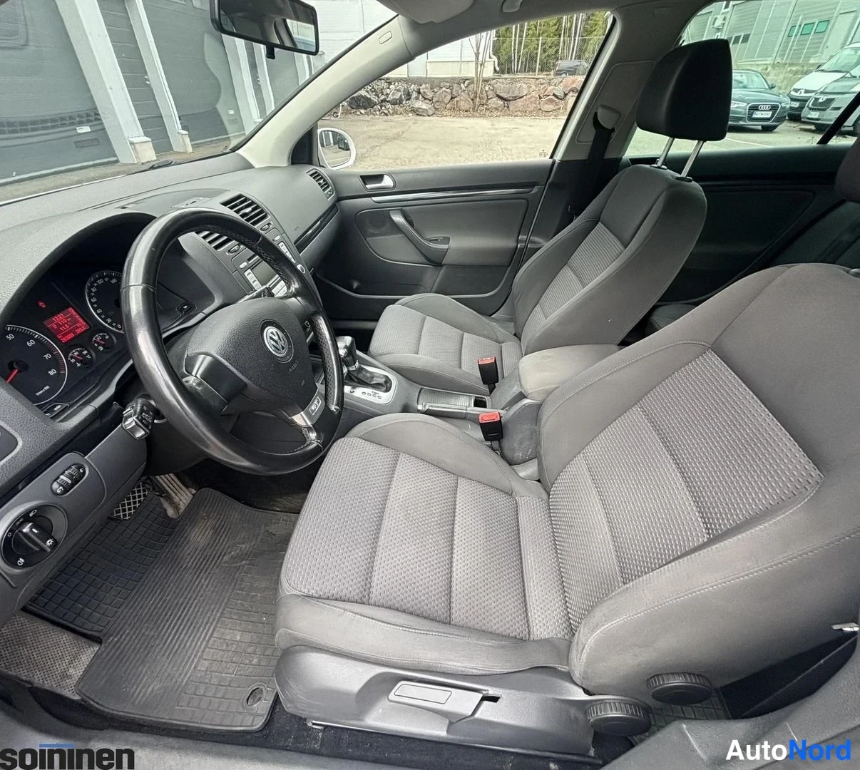 Edestä: Ohjaamo, ajetta, tummat penkit, Volkswagen-ohjauspyörä