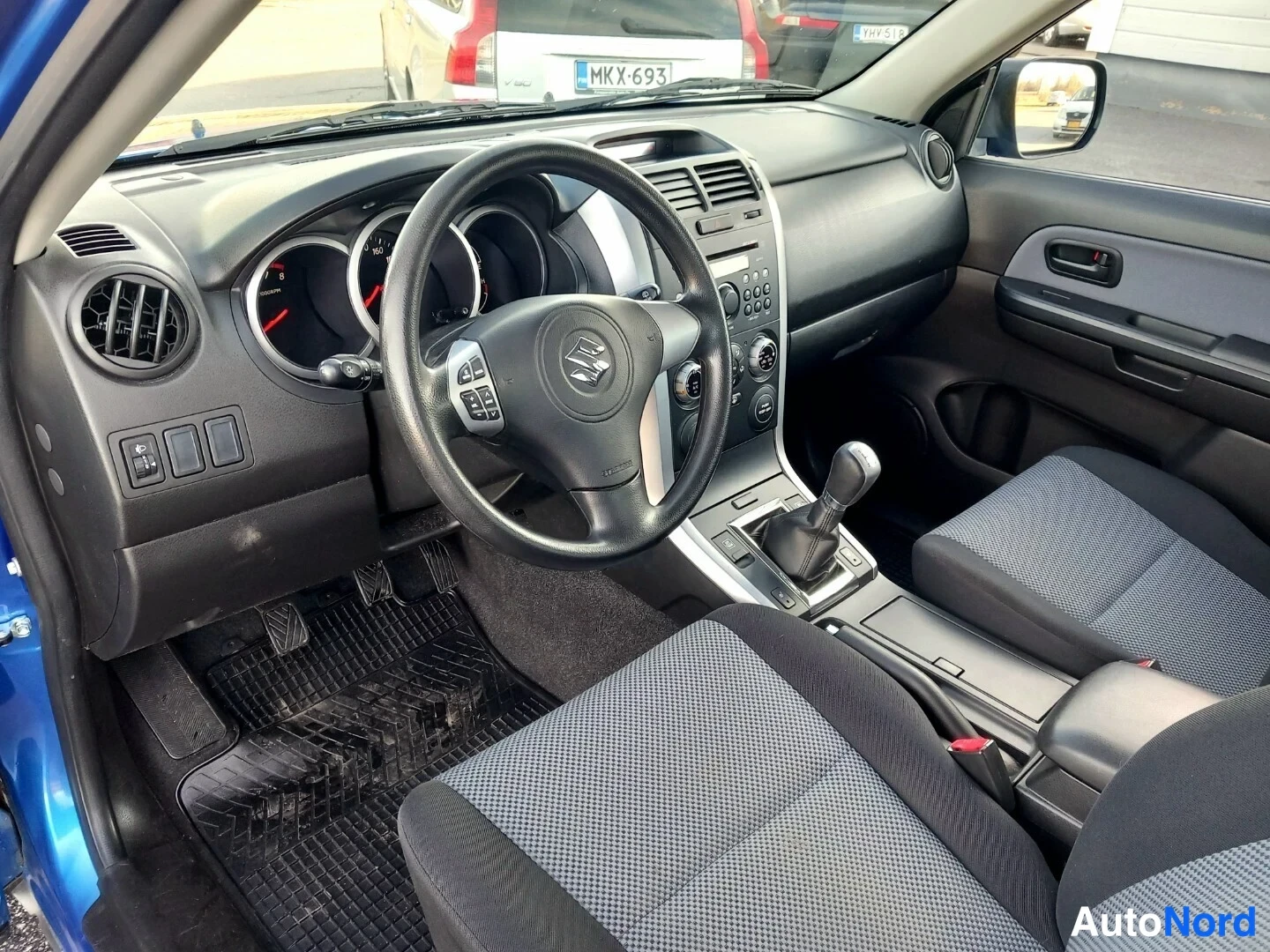 Muu: Ohjaamo vasemmalta: Suzuki-ohjauspyörä, mittaristo, automaattivaihteen valitsin, keskiöconsole ja kankaiset etuistuimet.