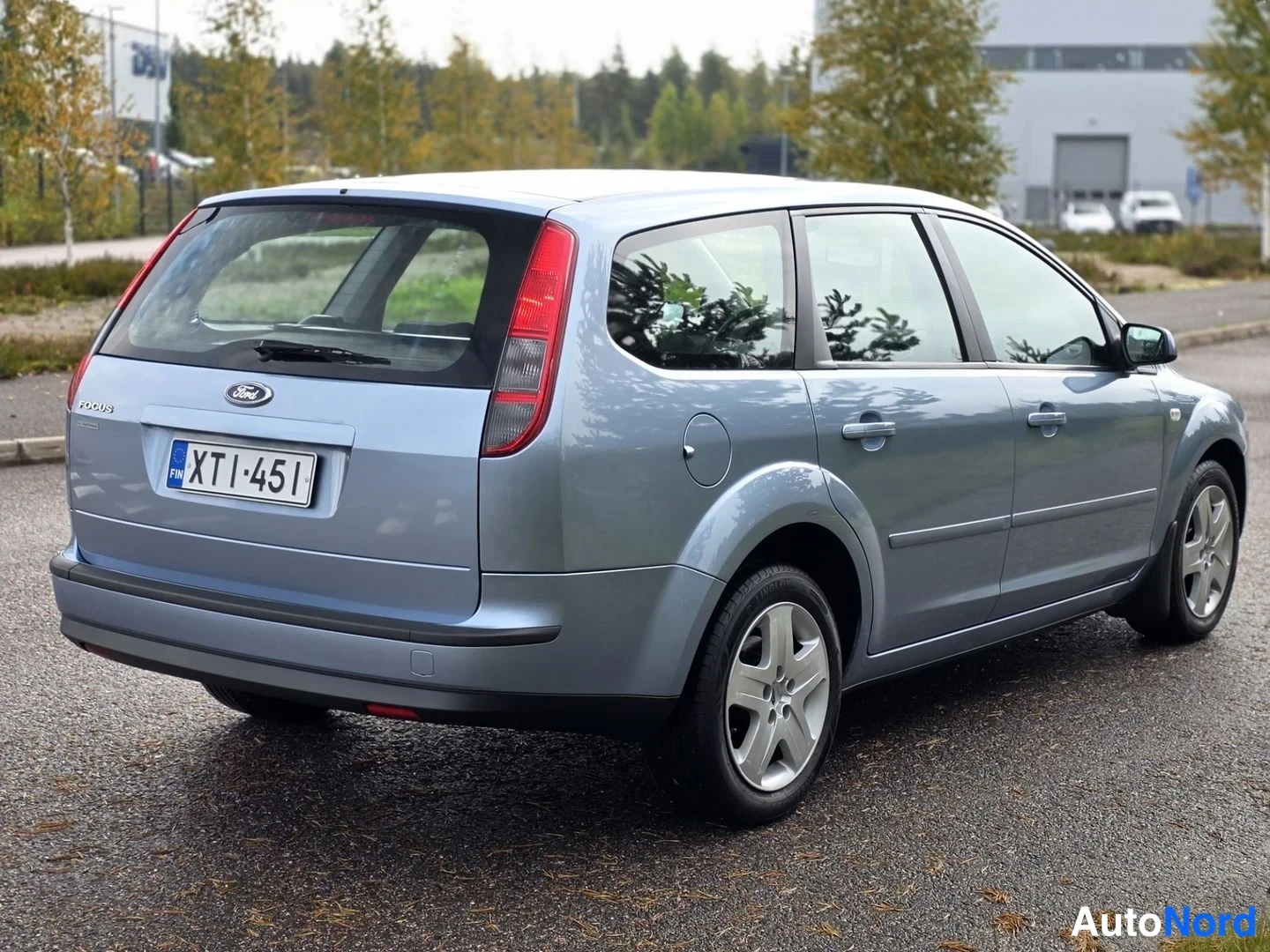 Takaviisto: Ford Focus -farmariauto takaa oikealta sivulta, harmaansininen kori, rekisterikilpi, parkkeerattuna asfaltille.