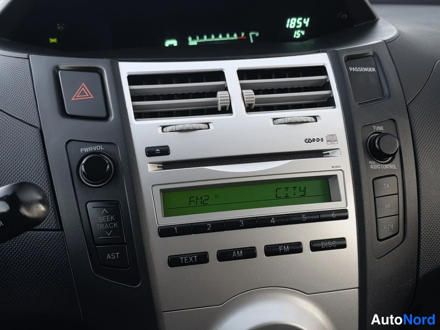 Muu: Kojelaudan keskikonsoli: radio näyttää FM2 City -kanavan, ylhäällä digitaalinen kellonäyttö 18:54 ja 15°, ilmastointisuuttimet ja äänentoiston painikkeet.