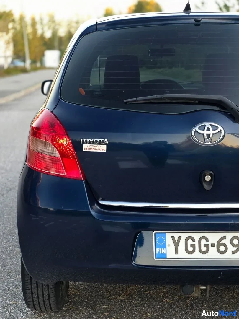 Takaa: Sinisen Toyota Yaris -henkilöautin takaosa lähikuvassa, takavalot, Toyota-merkki ja rekisteritunnus näkyvät.