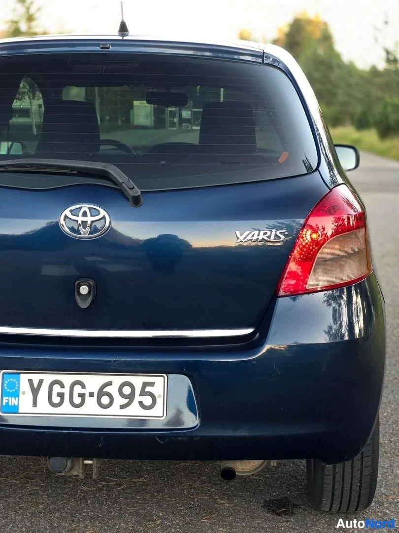 Takaa: Sinisen Toyota Yarisin takaosa; YARIS-teksti, Toyota-merkki, takanasuutin ja rekisteritunnus.