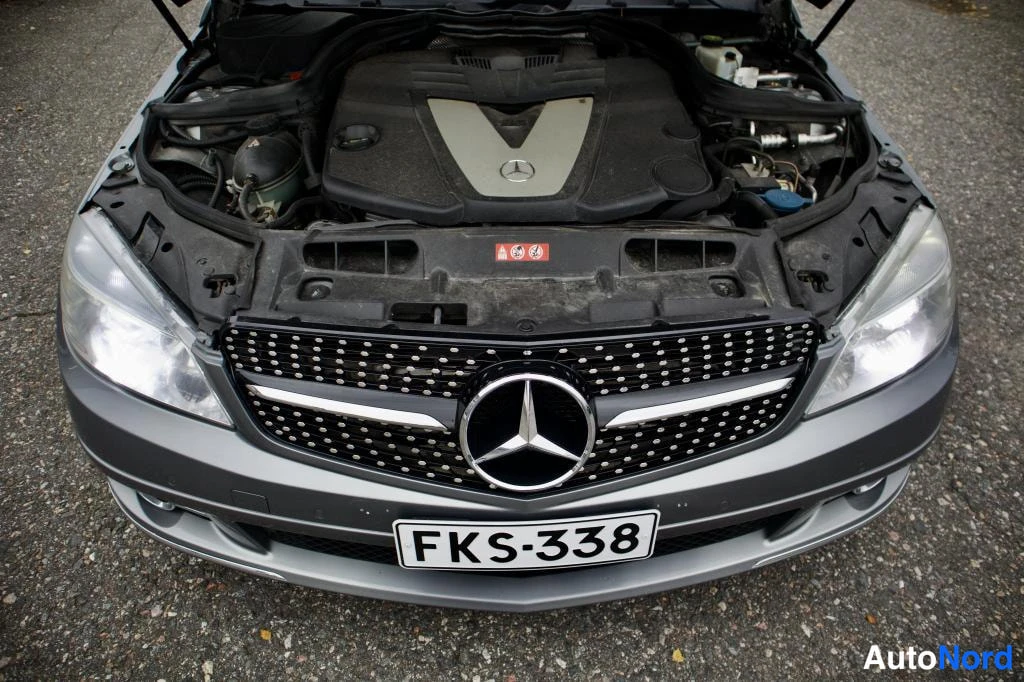 Edestä: Mercedes-henkiloauton etunakyma, konepelti auki ja moottoritila nakyy, rekisteritunnus.