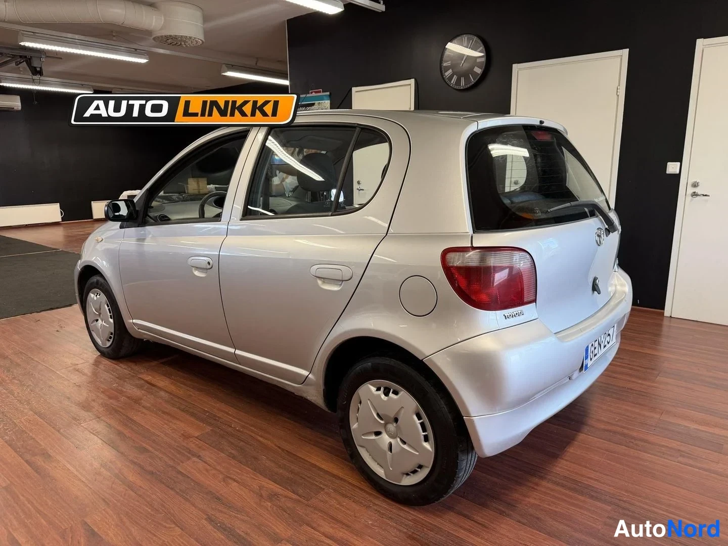 Takaviisto: Hopeanharmaa Toyota Yaris viistovalokuva takaa oikealta sisätiloissa.