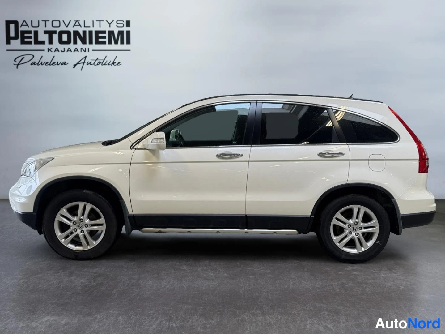 Sivulta: Valkoinen Honda CR-V sivusta kuvattuna sisätiloissa.