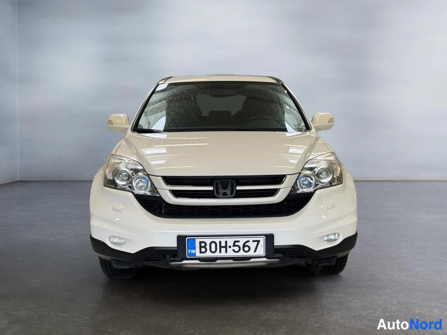 Edestä: Valkoisen Honda CR-V:n etupää suoraan edestä, rekisterikilpi.