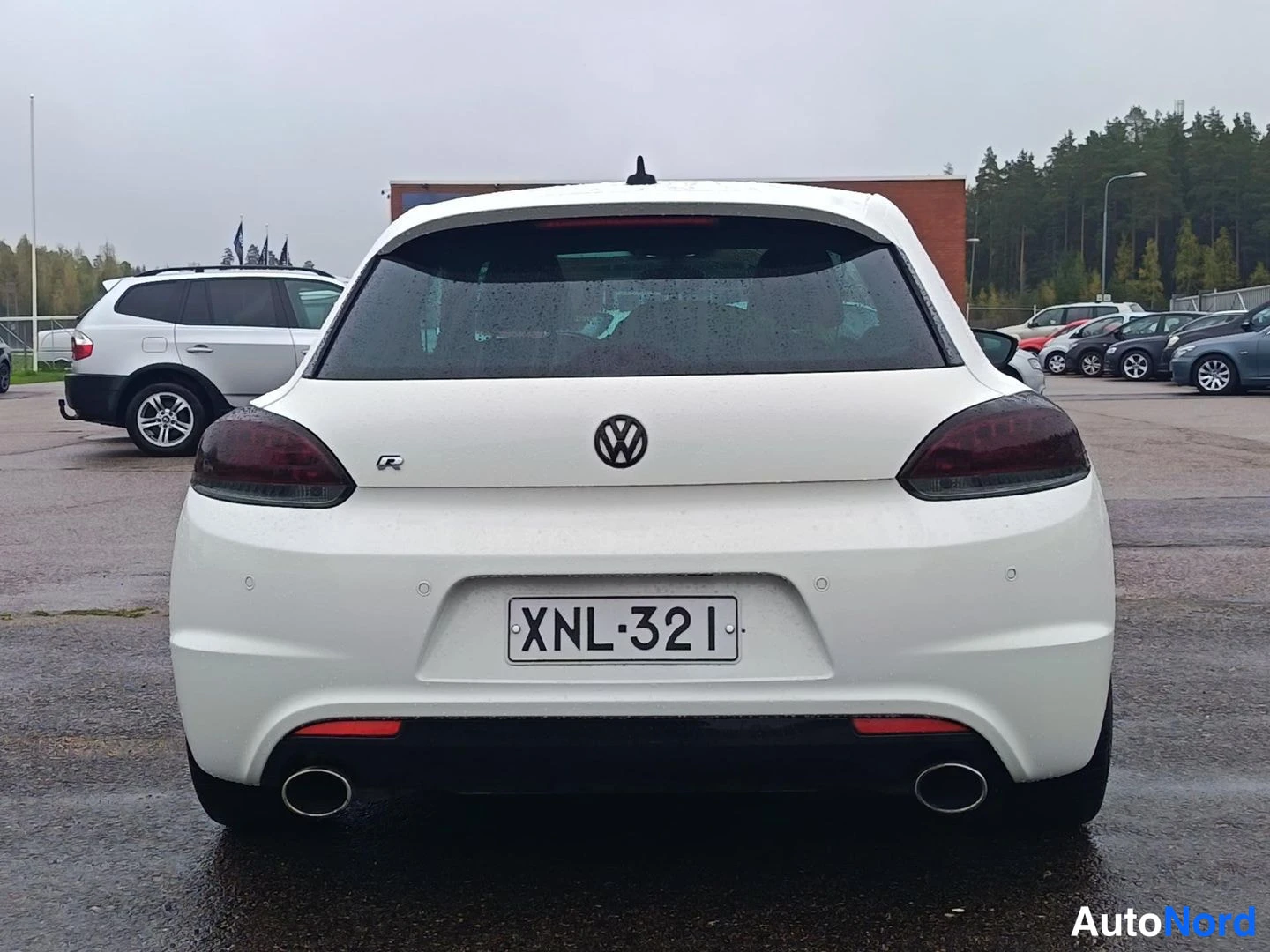Takaa: Valkoisen Volkswagen Scirocon takanäkymä, tummat takavalot, R-merkki ja kaksoispakoputket.