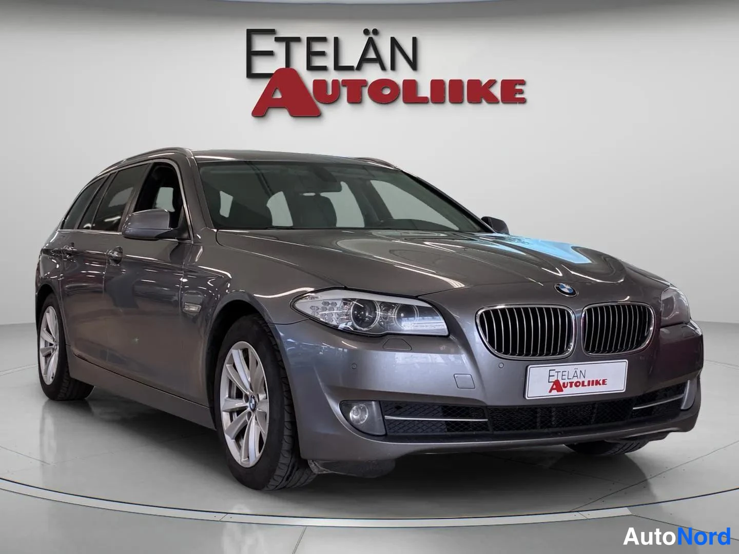 Etuviisto, nokka oikealle: Front three-quarter view of a grey BMW station wagon from the left side.