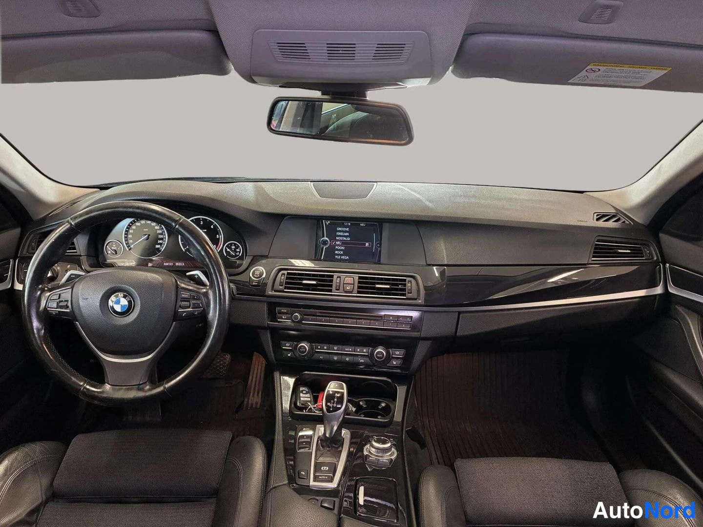 Yksityiskohta: BMW:n ohjaamo kuvattuna etupenkin kohdalta: vasemmalla oleva ohjauspyörä, kojelauta, radiovälineistö ja automaattivaihteen valitsin.