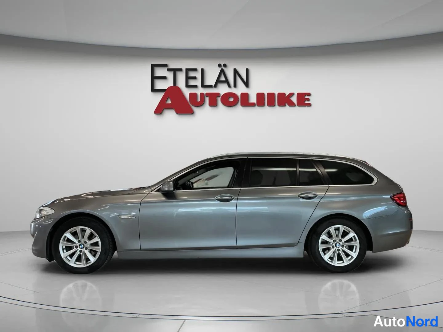 Sivulta: Side profile view of a grey BMW station wagon.