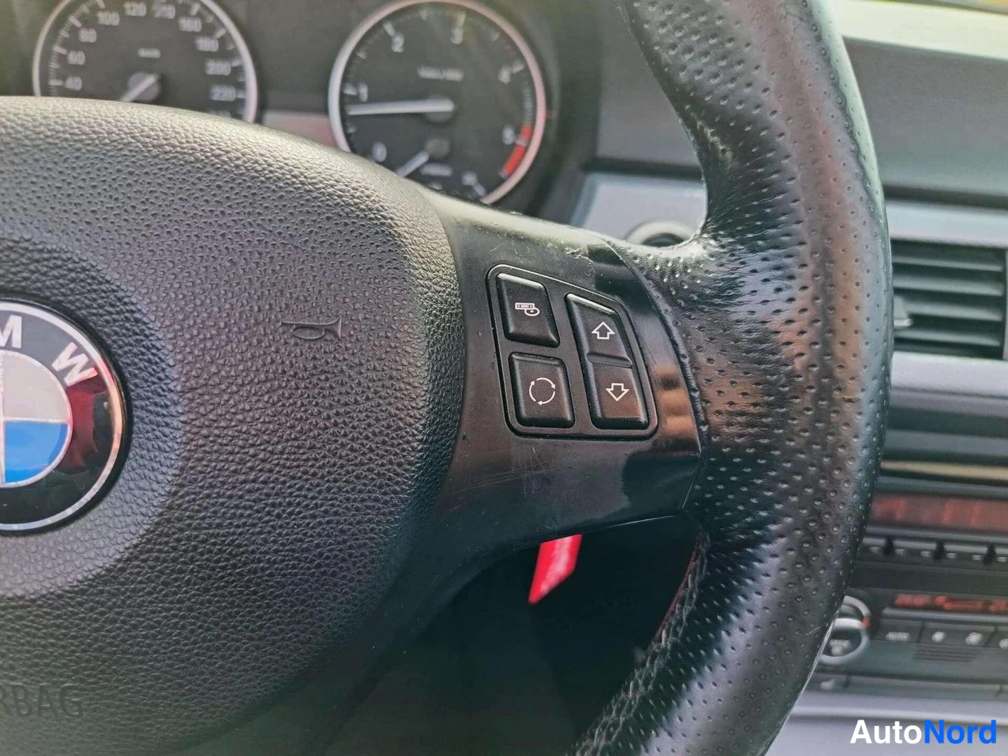Muu: Lähikuva ohjauspyörän oikeasta kyljestä: ESL- ja lämmitysnäppäimet, BMW-logon reuna ja AIRBAG-teksti.