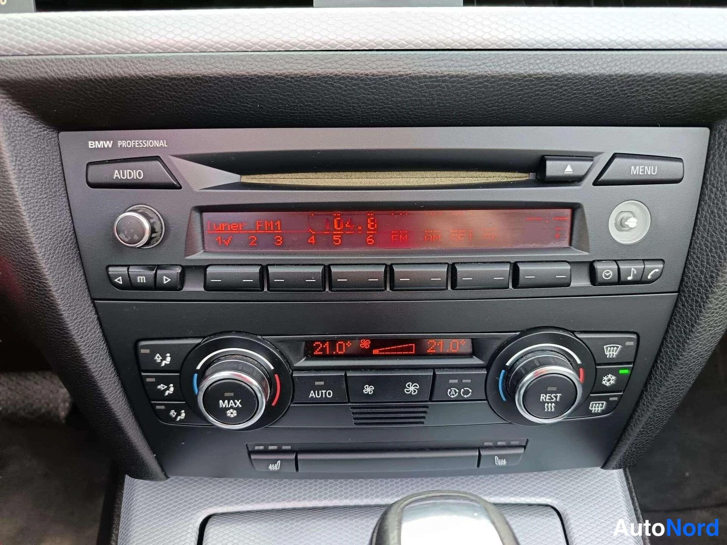 Muu: Keskitelineen lähikuva: BMW Professional -radio/navigaatioyksikkö AUDIO- ja MENU-painikkeilla, näyttötekstillä 'FM1 04:8', sekä kaksivyöhykeilmastointi (21.0° m