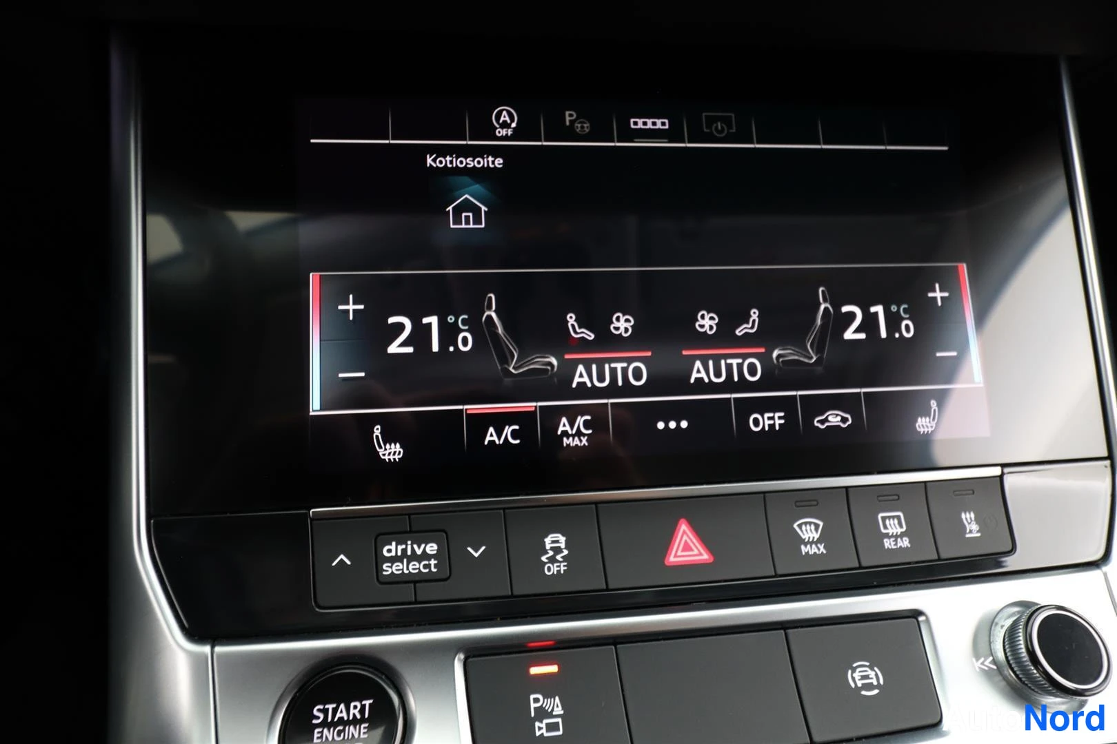 Etuviisto, nokka vasemmalle: Kojelaudan ilmastointinäyttö näyttää 21 astetta molemmin puolin, AUTO-tila ja A/C päällä, alla drive select -painike.