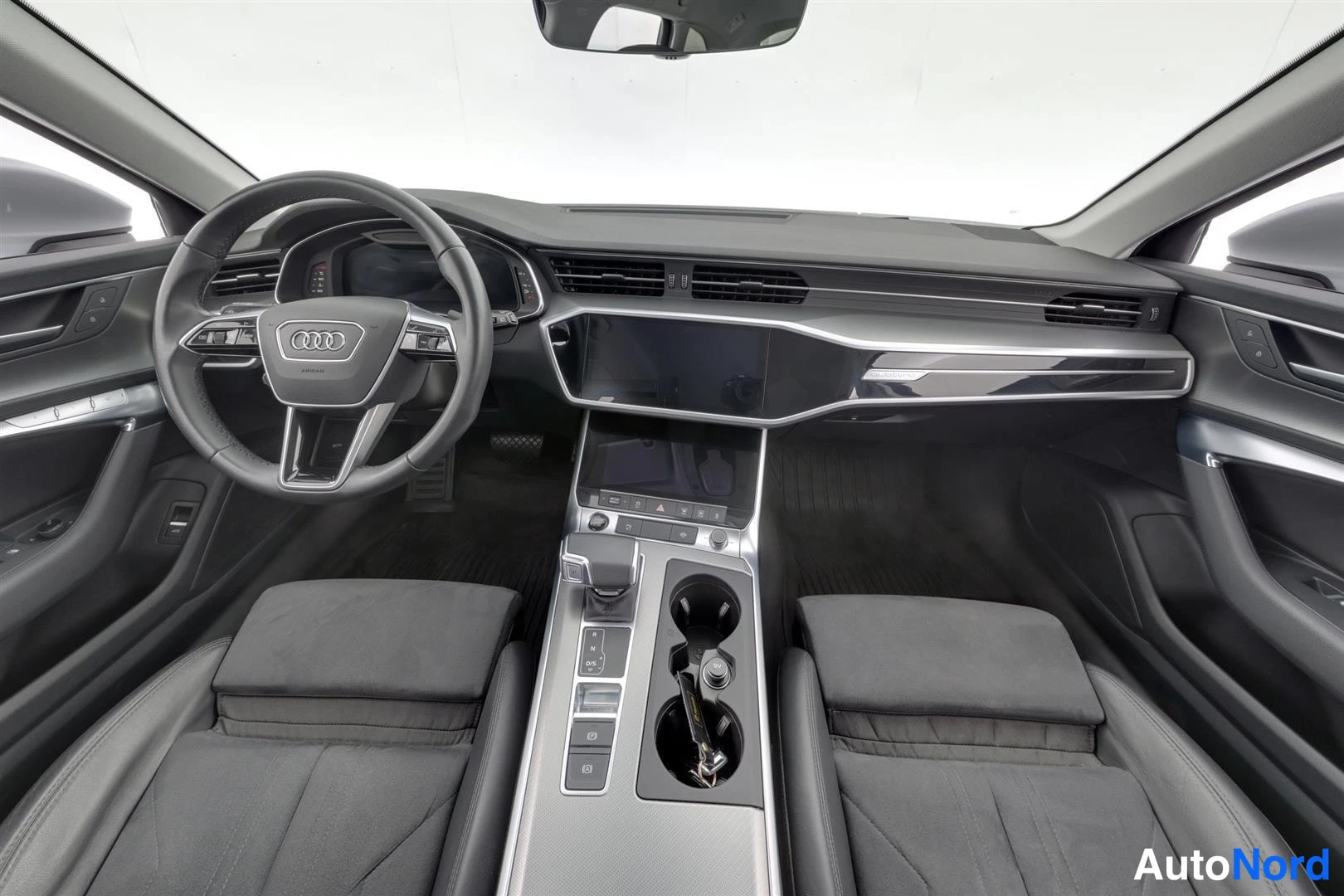 Muu: Ohjaamo ylhäältä etuosalta: Audi-ohjauspyörä, tumma kojelauta ja keskikonsoli, kaksi etuistuinta.