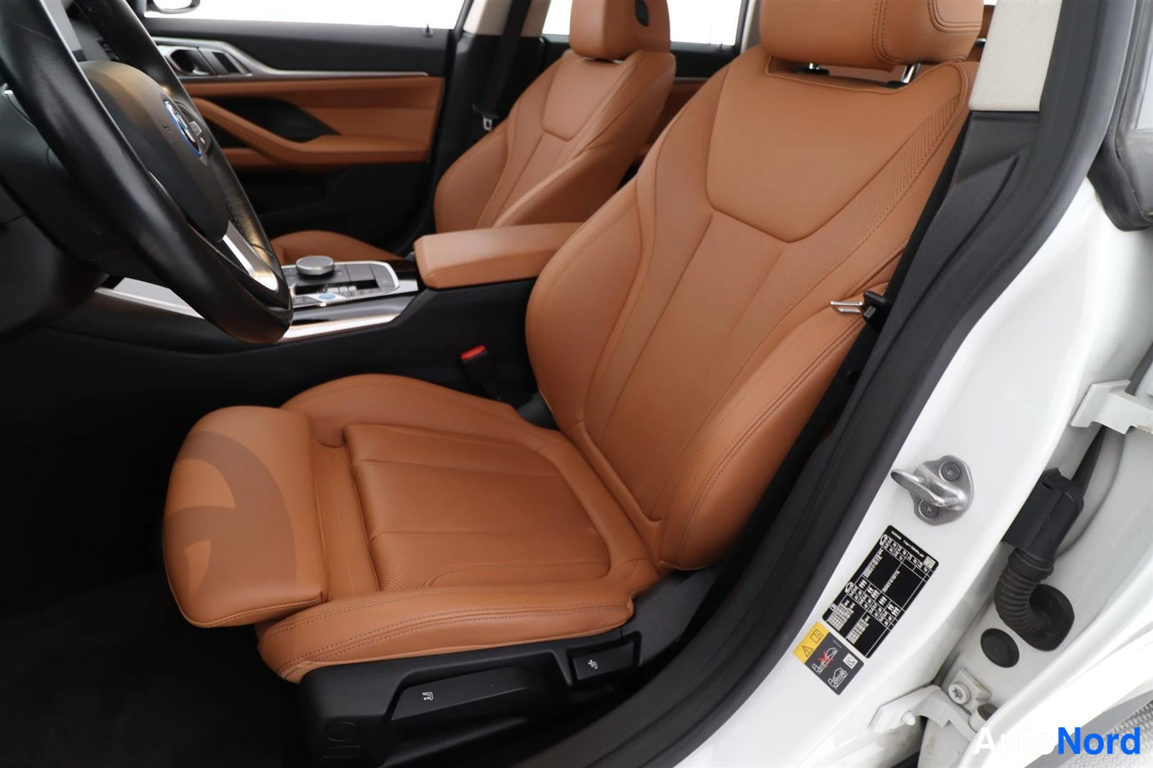 Etuistuimet: Interior view of the front seats from the driver's side door opening. Two tan-colored leather bucket seats are visible in the foreground and mid-ground. A porti