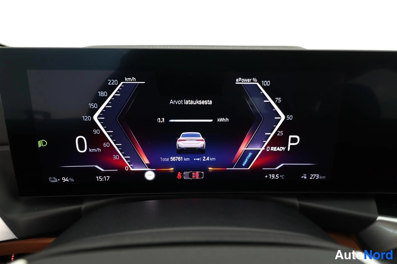 Ohjaamo: Digital instrument cluster display screen. On the left, a speedometer reads 0 km/h. Center text reads 'Arvot latauksesta'. Below an icon of the car, it reads 'T