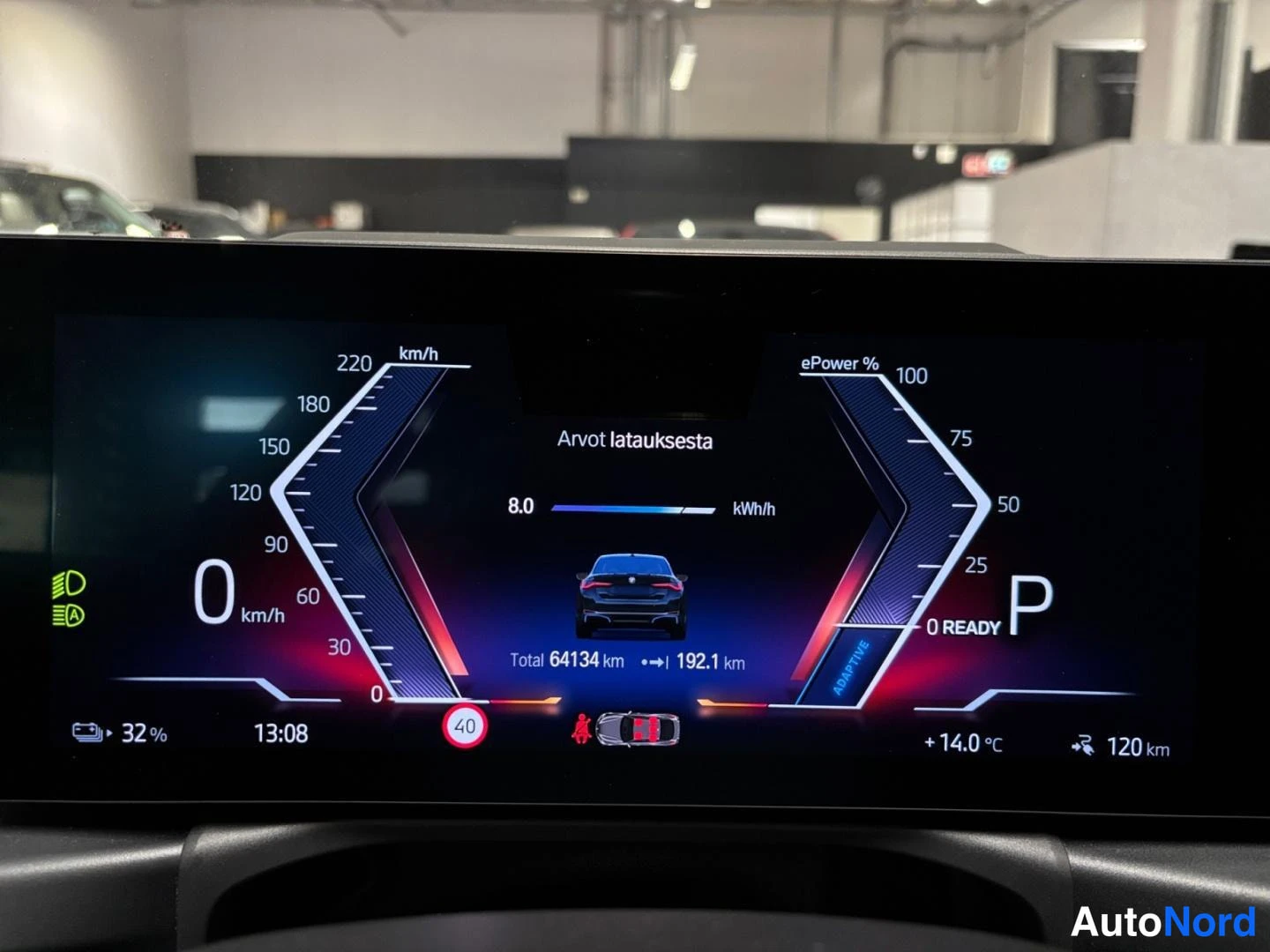 Yksityiskohta: Digitaalisen kojelaudan näyttö lähikuvassa: lataustiedot 8.0 kWh/h, ajettu 64134 km, vaihde P, kellonaika 13:08, ulkolämpötila +14.0 °C.