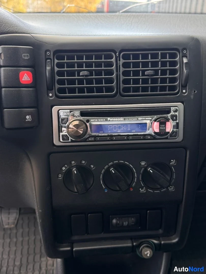 Muu: Keskikonsoli ylhäältä: Panasonic CQ-R221N radio, ilmastointiaukot, kolme säätö nappia ja varoituskolmio painike.