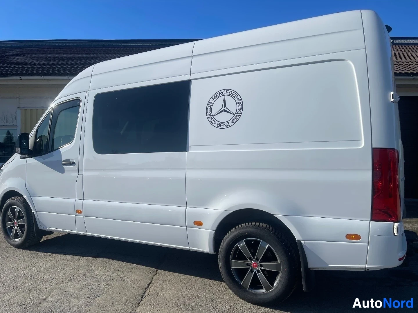 Takaviisto: Valkoinen Mercedes-Benz Sprinter -pakettiauto taka kulmasta, oikea kylki ja perä näkyvissä, Mercedes-Benz-logolla sivussa.