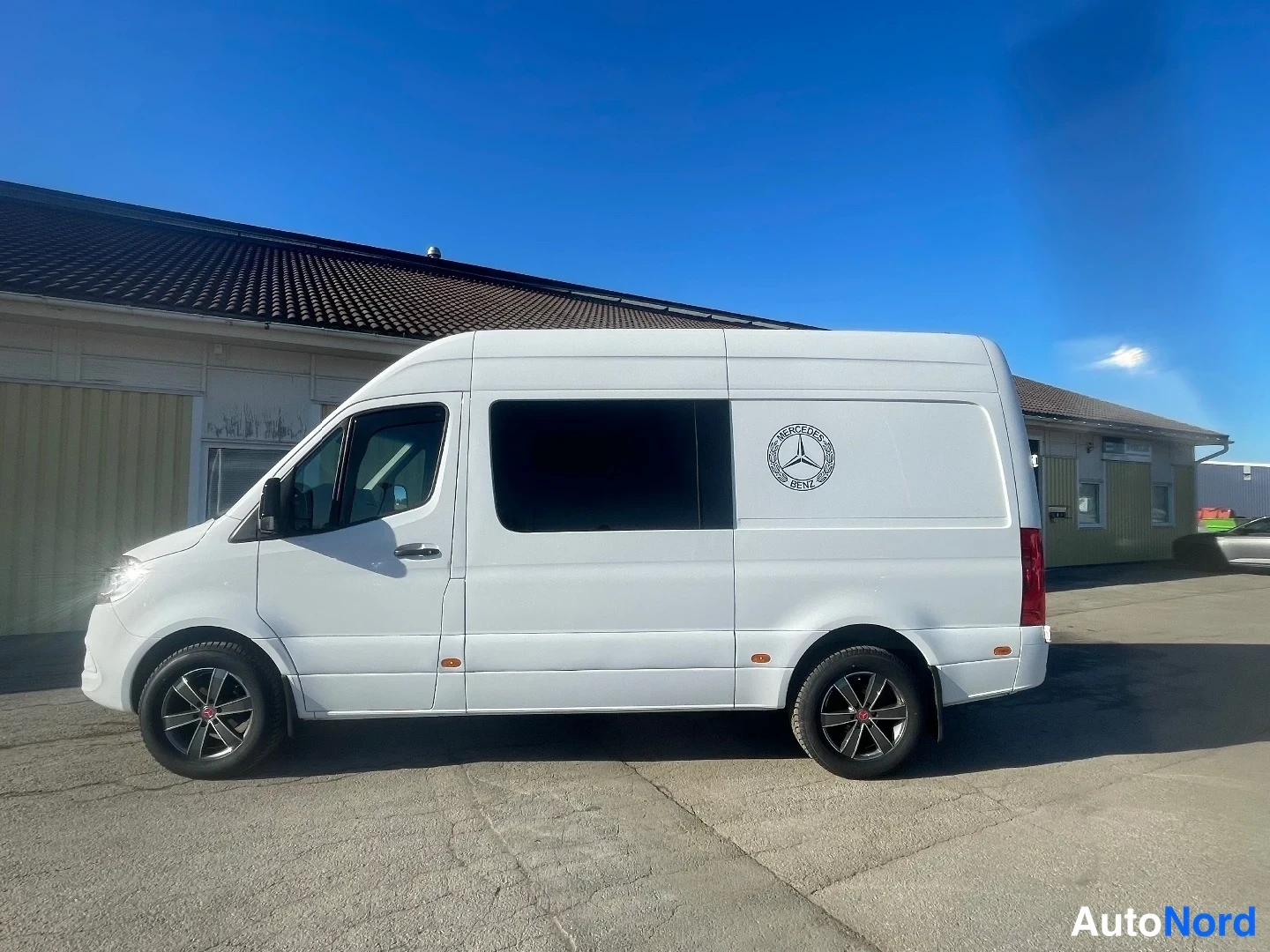 Etuviisto, nokka vasemmalle: Valkoinen Mercedes-Benz Sprinter -pakettiauto sivulta etukolmasosa, tummat kevytmetallivanteet.